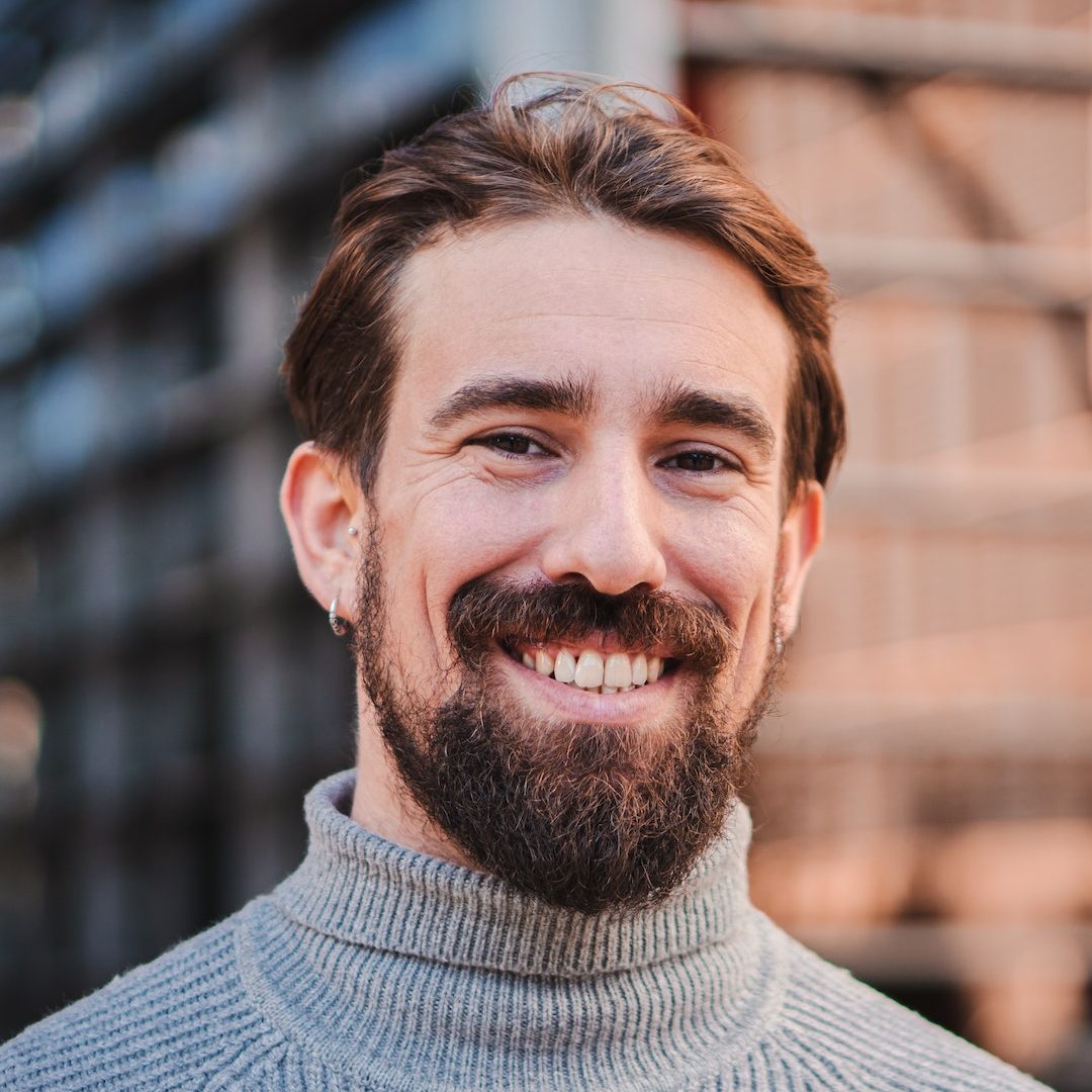 Close up portrait of awesome young caucasian male smiling and looking at camera at the background e1682562299624.jpg